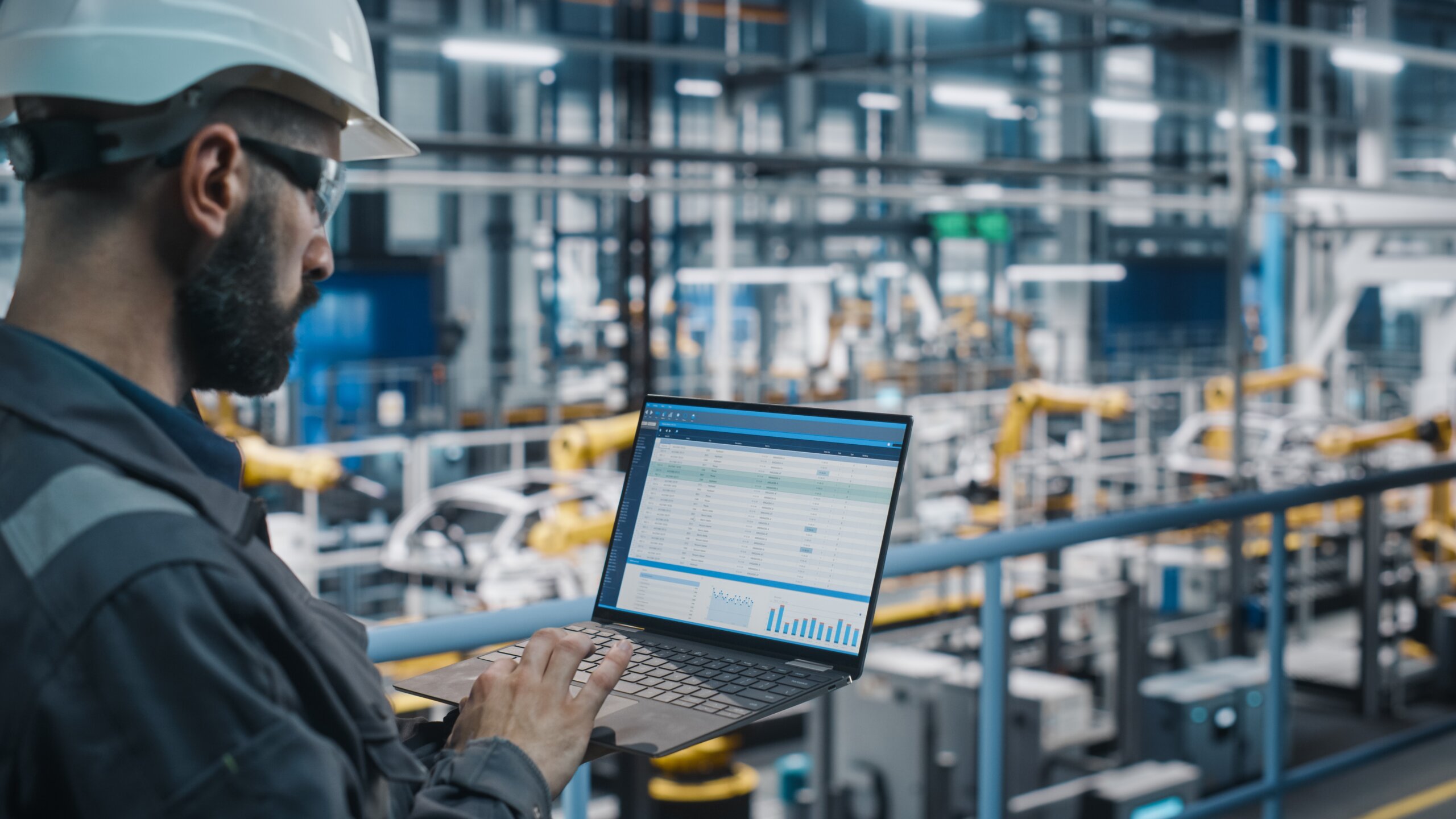 Professional using Growvex analytics dashboard on laptop in industrial facility showing procurement data and charts